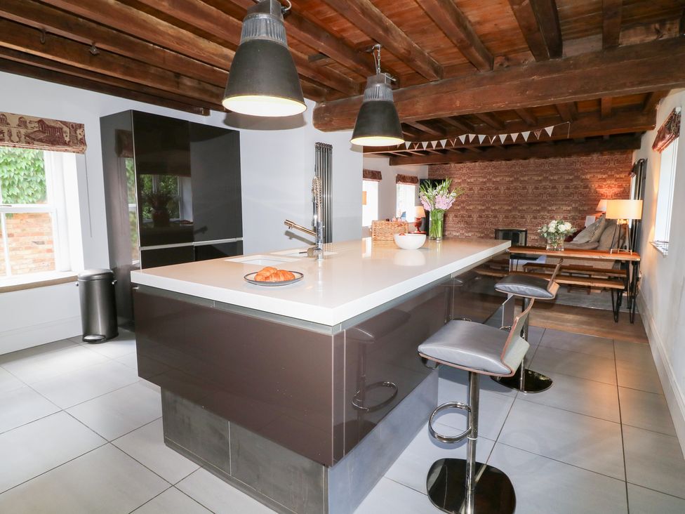 A kitchen with an island and bar stools at The Old Barn in Caenby near Market Rasen