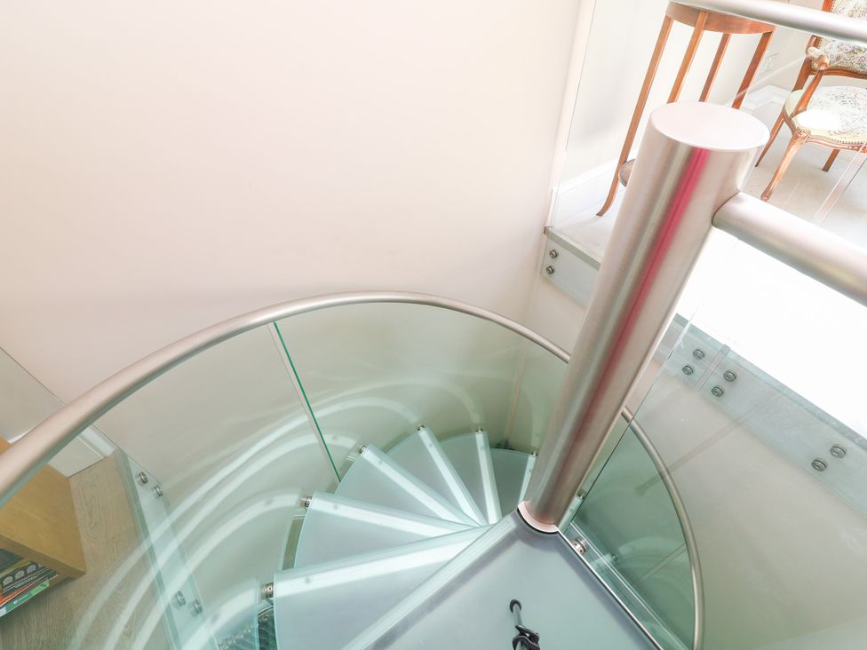 A spiral staircase with glass railing at The Old Barn in Caenby near Market Rasen