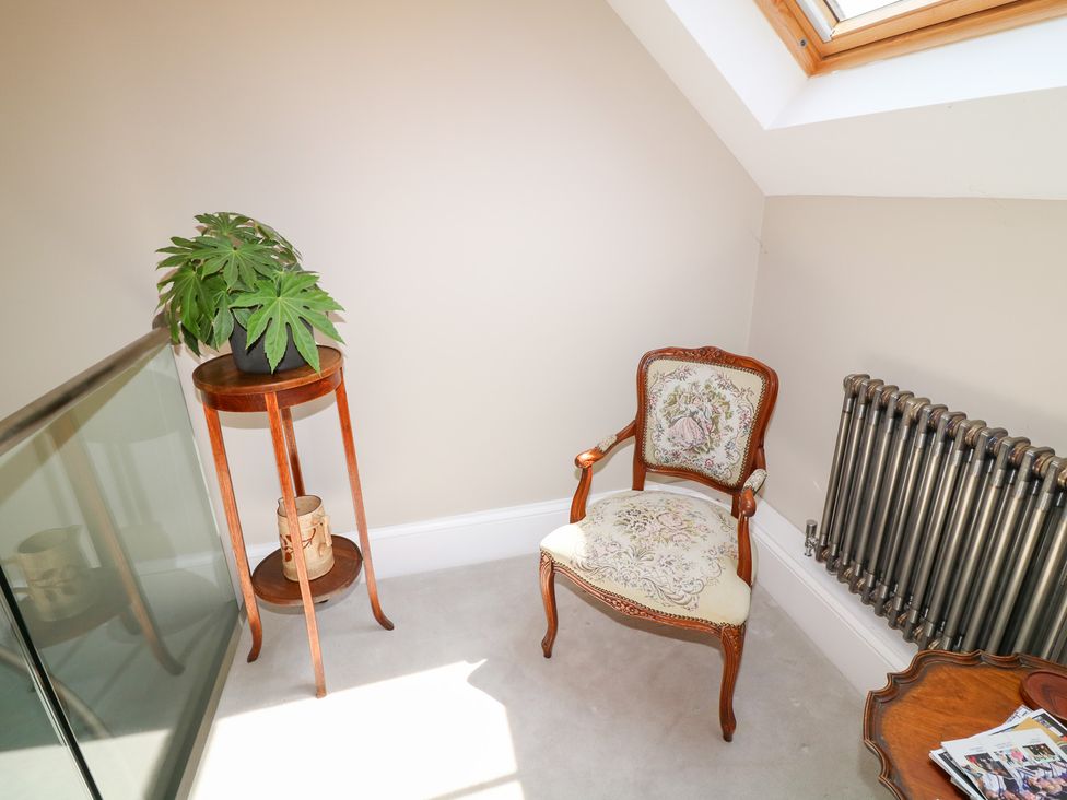 A snug with a chair, table, plant, and radiator at The Old Barn in Caenby near Market Rasen