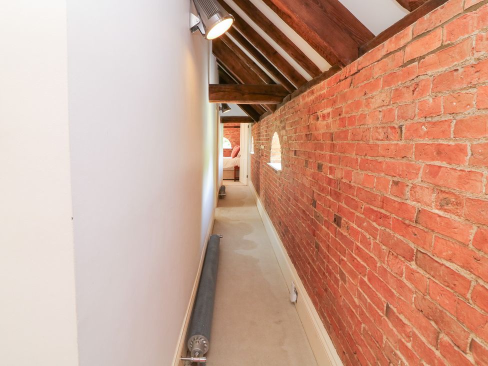 A hallway with brick walls and light fixture at The Old Barn in Caenby near Market Rasen