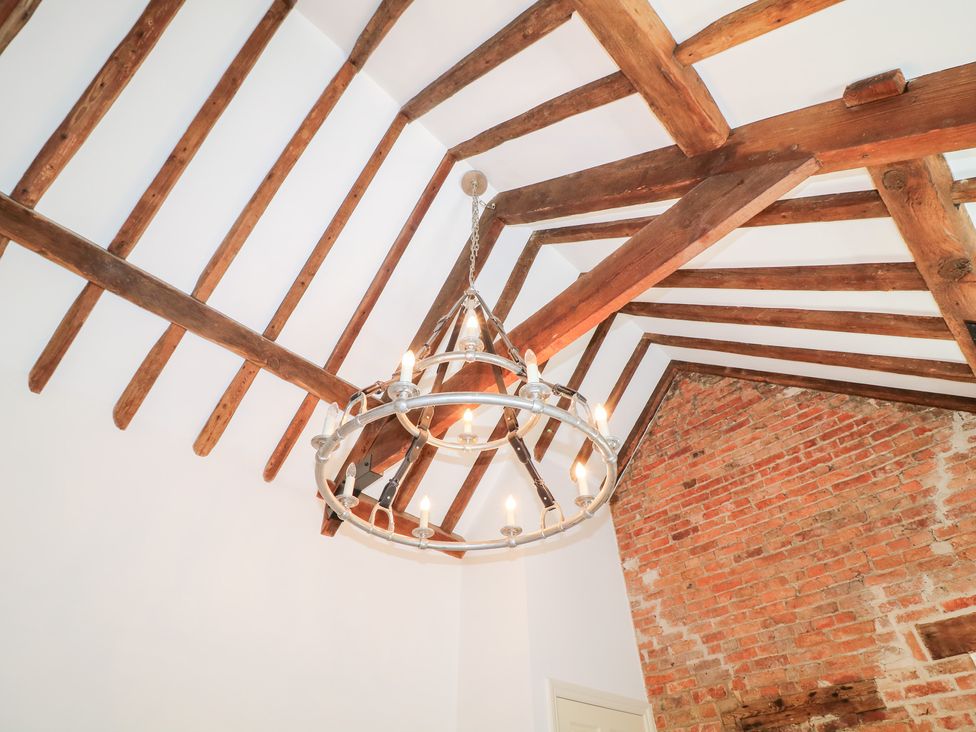 A ceiling with wood beams and a chandelier at The Old Barn in Caenby near Market Rasen