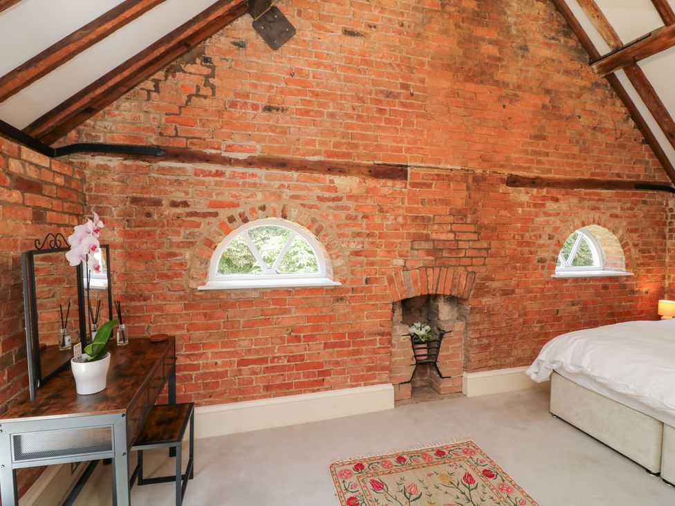 A bedroom with brick walls and a desk at The Old Barn in Caenby near Market Rasen