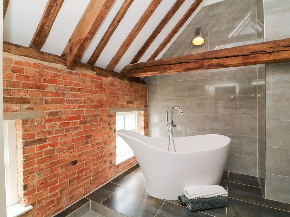 A bathroom with a bathtub and brick walls at The Old Barn in Caenby near Market Rasen