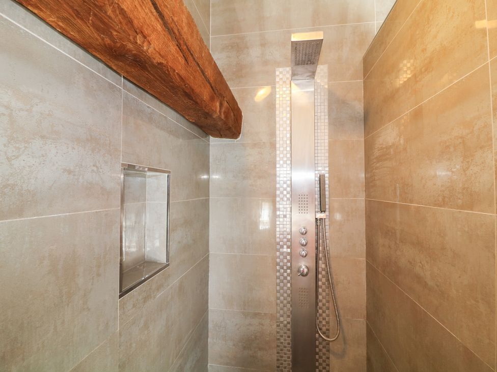A shower with a shower fixture and wall shelf at The Old Barn in Caenby near Market Rasen