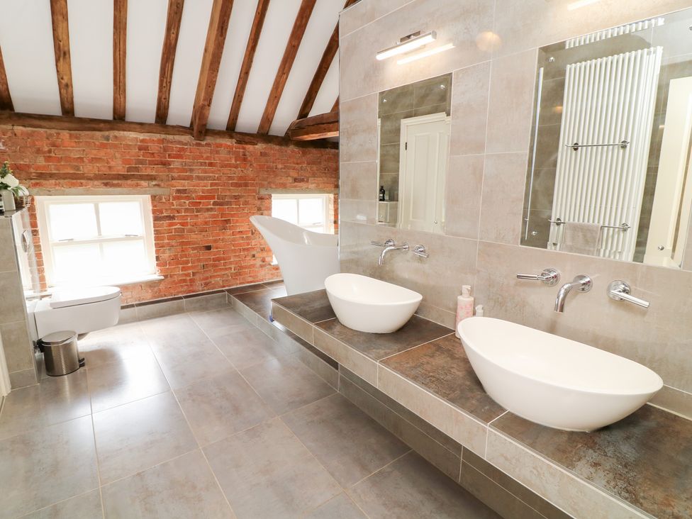A bathroom with sinks and a bathtub at The Old Barn in Caenby near Market Rasen