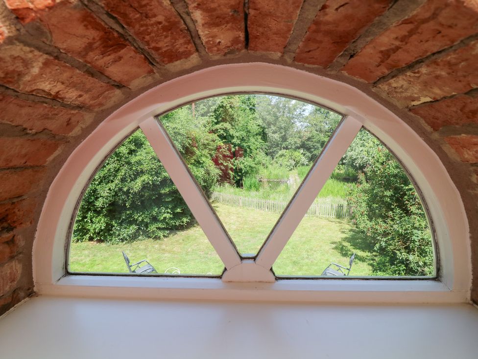 A view of a garden through an arched window at The Old Barn in Caenby near Market Rasen