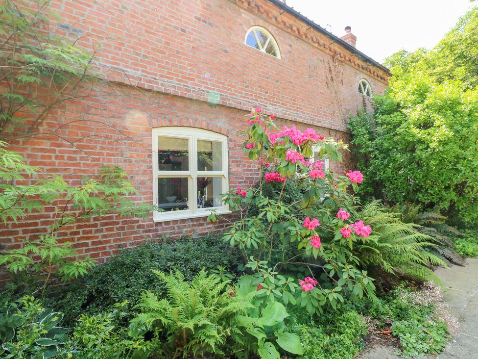 A garden view showing a brick wall, window and plants at The Old Barn in Caenby near Market Rasen