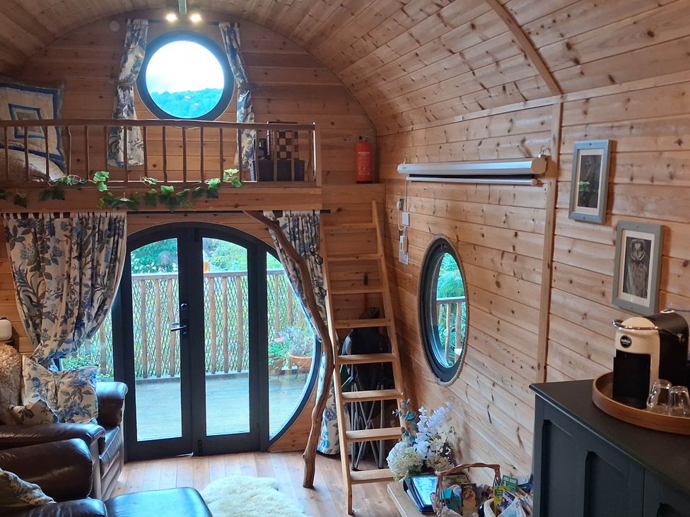 A living room with a round window and a ladder at The Kites Nest in Pont-rhyd-y-groes near Pontrhydfendigaid, Snowdonia