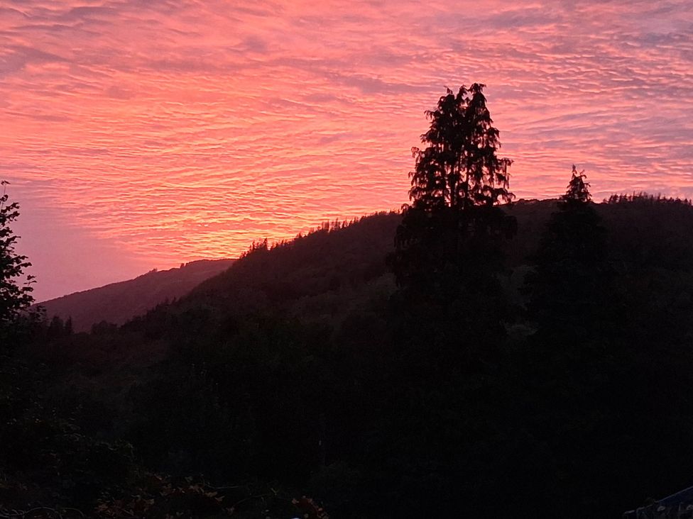 A sunset over mountains with silhouetted trees at The Kites Nest in Pont-rhyd-y-groes near Pontrhydfendigaid, Snowdonia