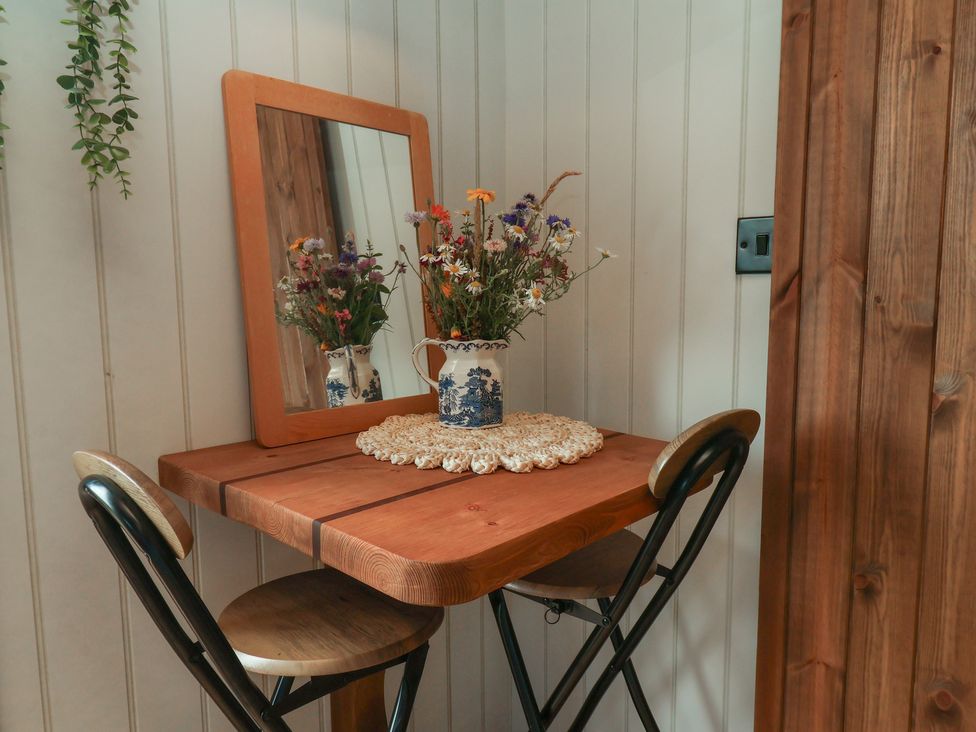 A small table with a flower vase and mirror at Lodge Farm in Whitby