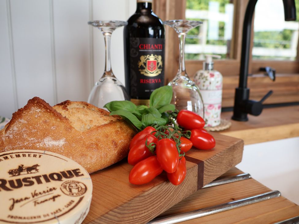 A kitchen counter with bread, tomatoes, cheese, and a wine bottle at Lodge Farm in Whitby