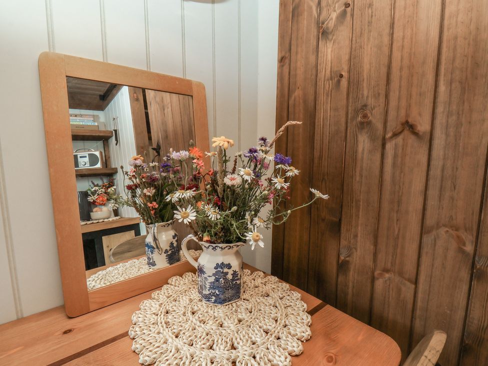A table with a flower vase and mirror at Lodge Farm in Whitby