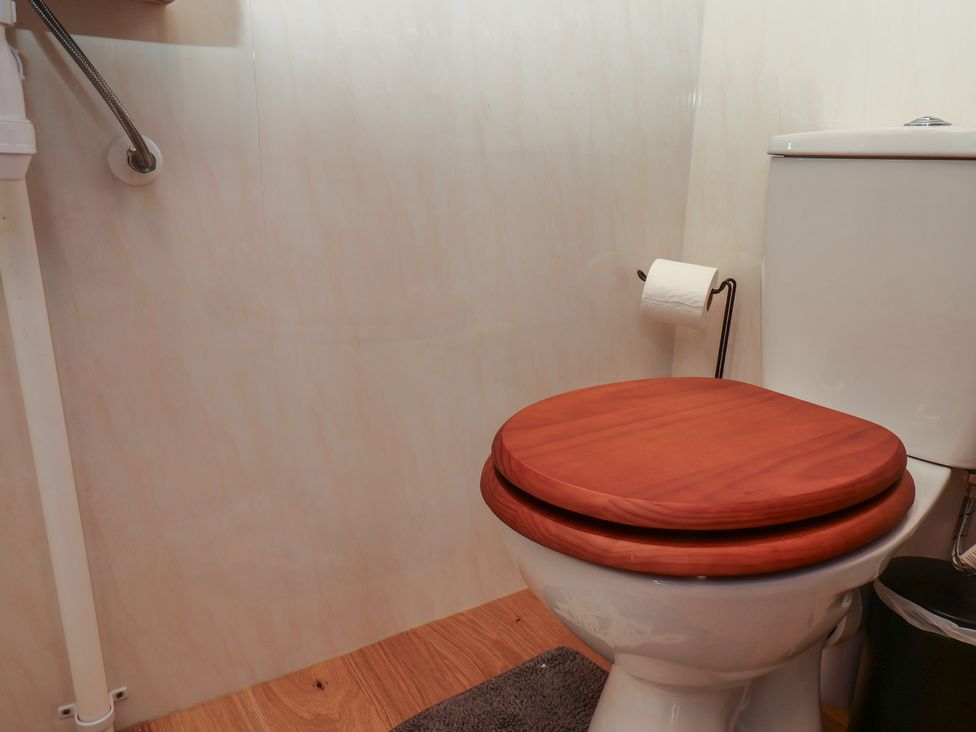 A bathroom with a toilet and toilet paper holder at Lodge Farm in Whitby