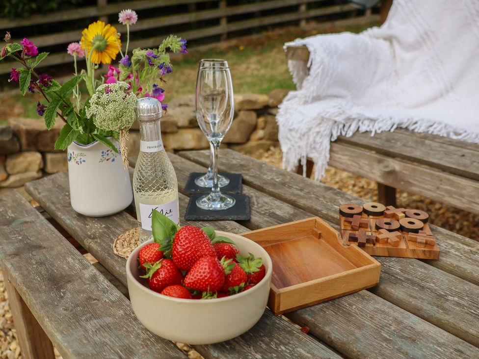 An outdoor seating area with strawberries, champagne, and flowers at Lodge Farm in Whitby