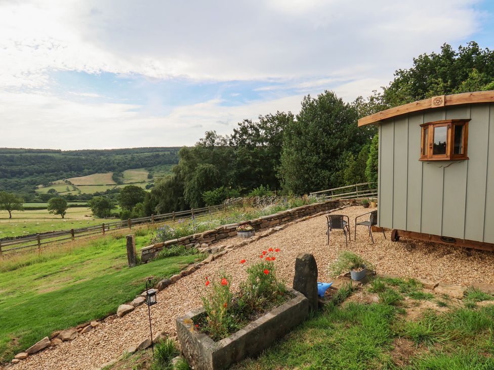 An outdoor area with a shepherd's hut and chairs at Lodge Farm in Whitby