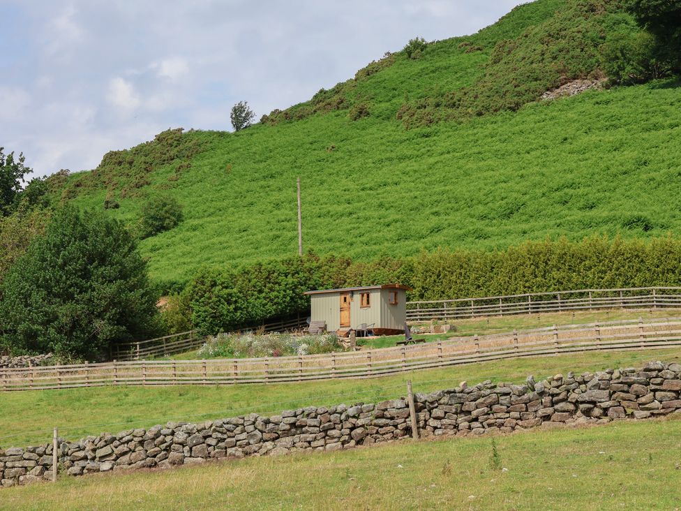 A shepherd's hut near a hill with a fence at Lodge Farm in Whitby