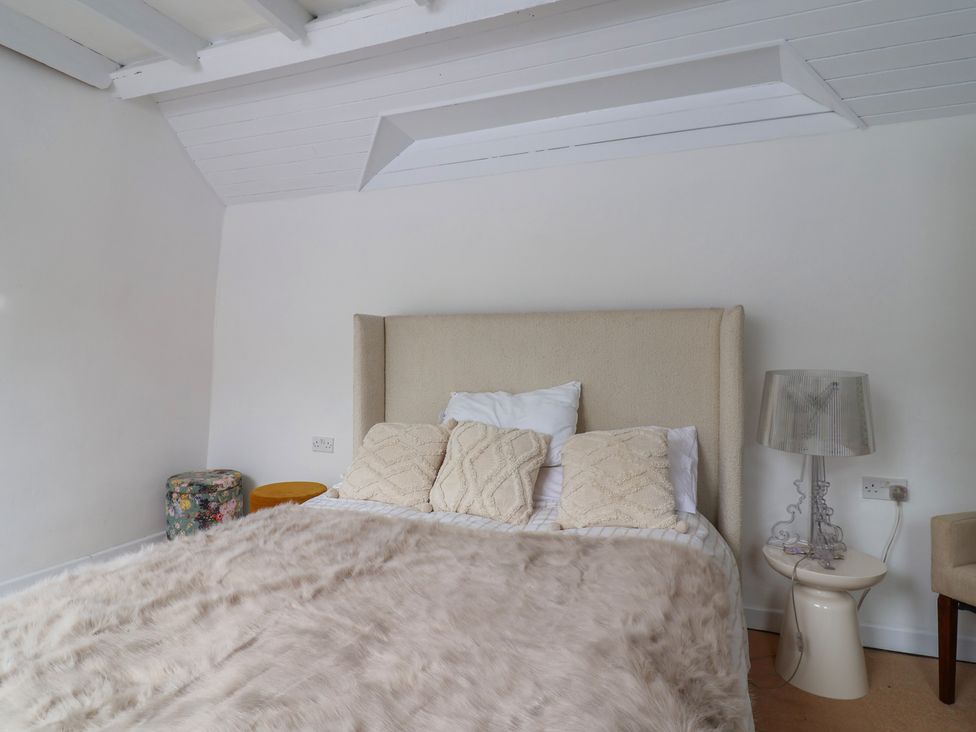 A bedroom with a bed and lamp at The Studio Cottage in Denbigh
