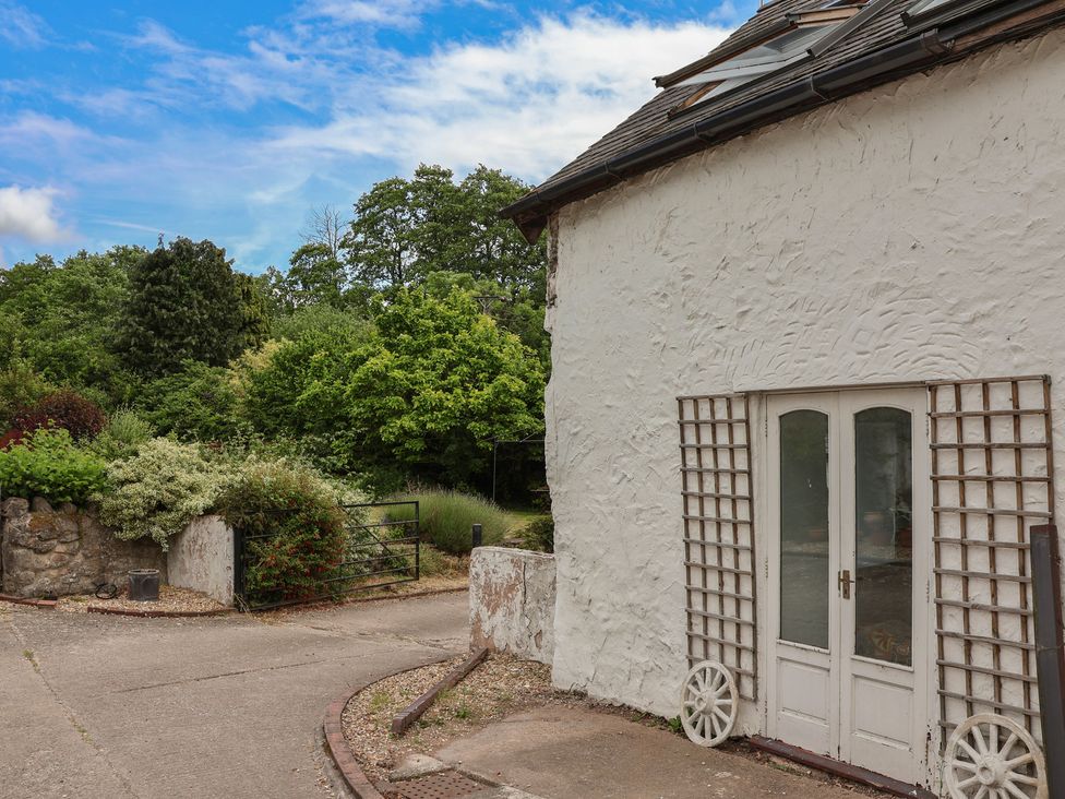 An exterior view of a white cottage with a garden and pathway at The Studio Cottage in Denbigh