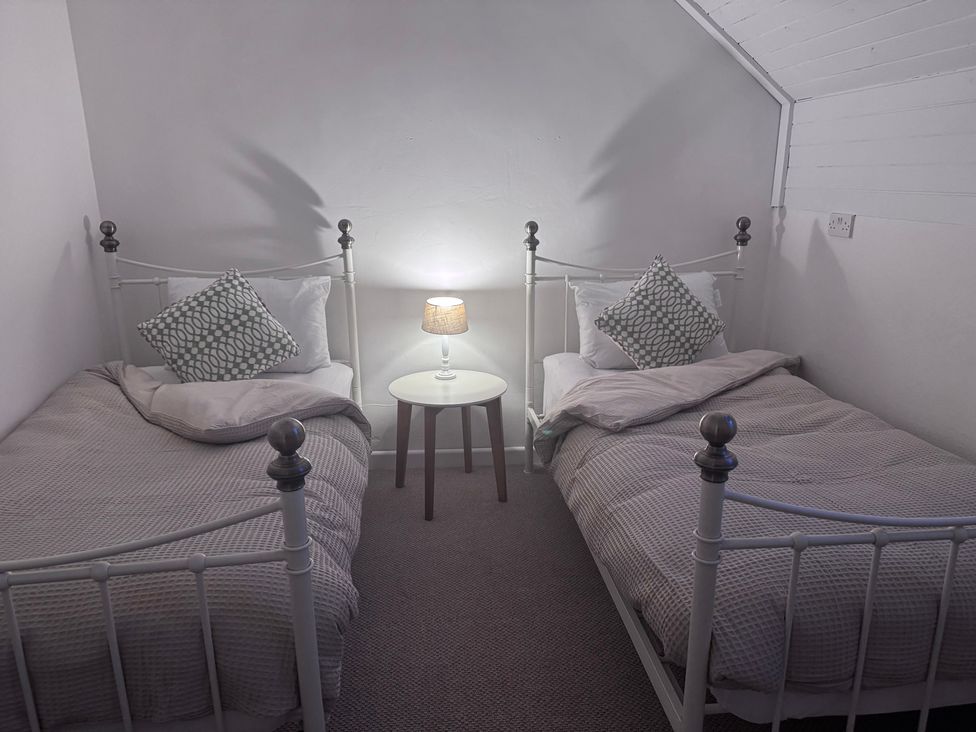 A bedroom with two beds and a lamp on a side table at The Studio Cottage near Denbigh