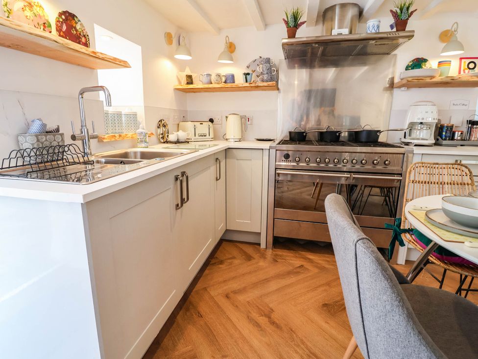 A kitchen with a stove, sink, and modern appliances at The Studio Cottage near Denbigh