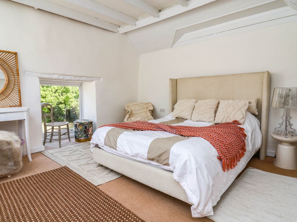 A bedroom with a bed, lamp, and a mirror at The Studio Cottage near Denbigh