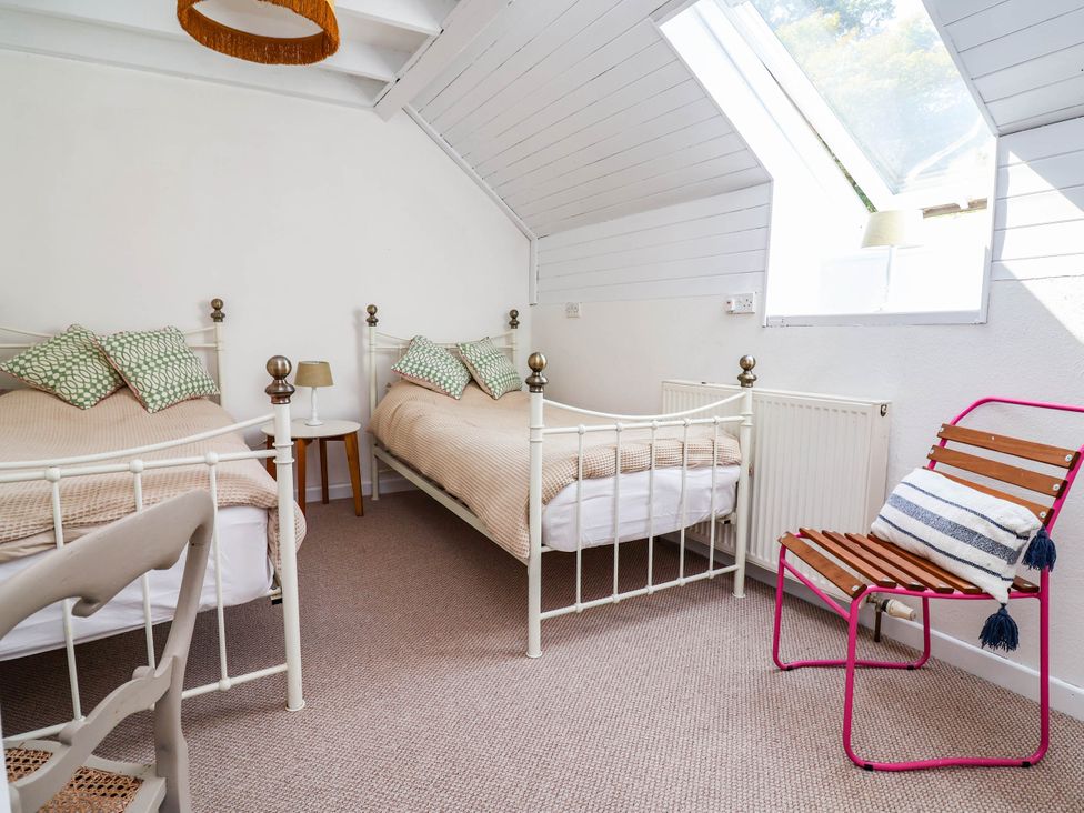 A bedroom with two beds and a chair at The Studio Cottage near Denbigh