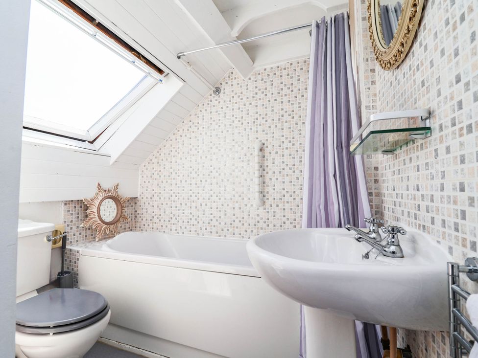 A bathroom with a bathtub, sink, mirror and toilet at The Studio Cottage near Denbigh