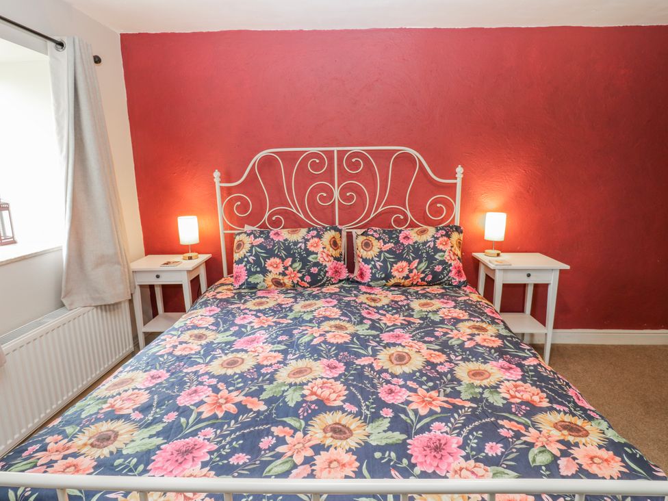 A bedroom with a floral bed and bedside tables at The Granary in Ellingstring near Masham