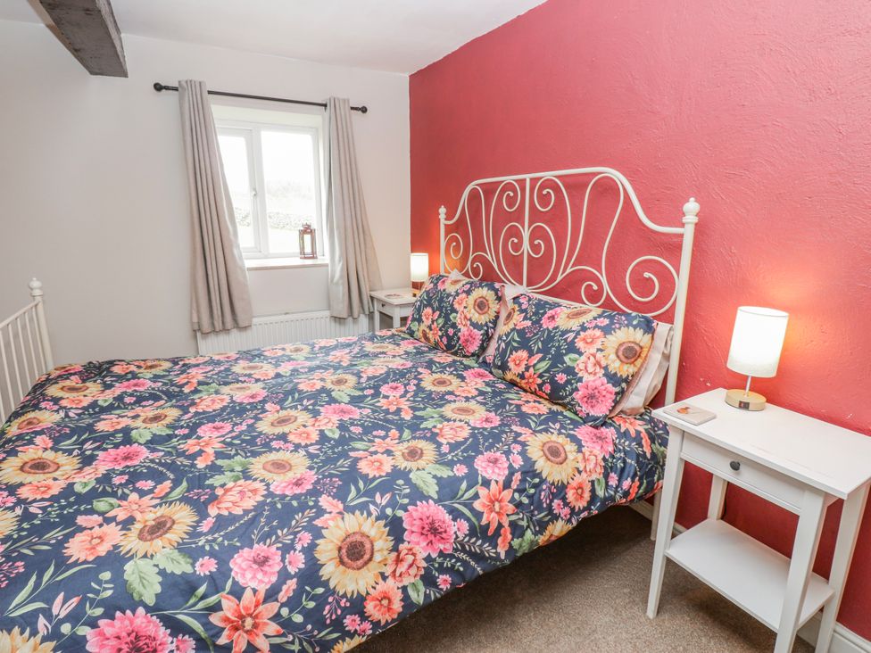 A bedroom with a floral bed cover and bedside table at The Granary in Ellingstring near Masham