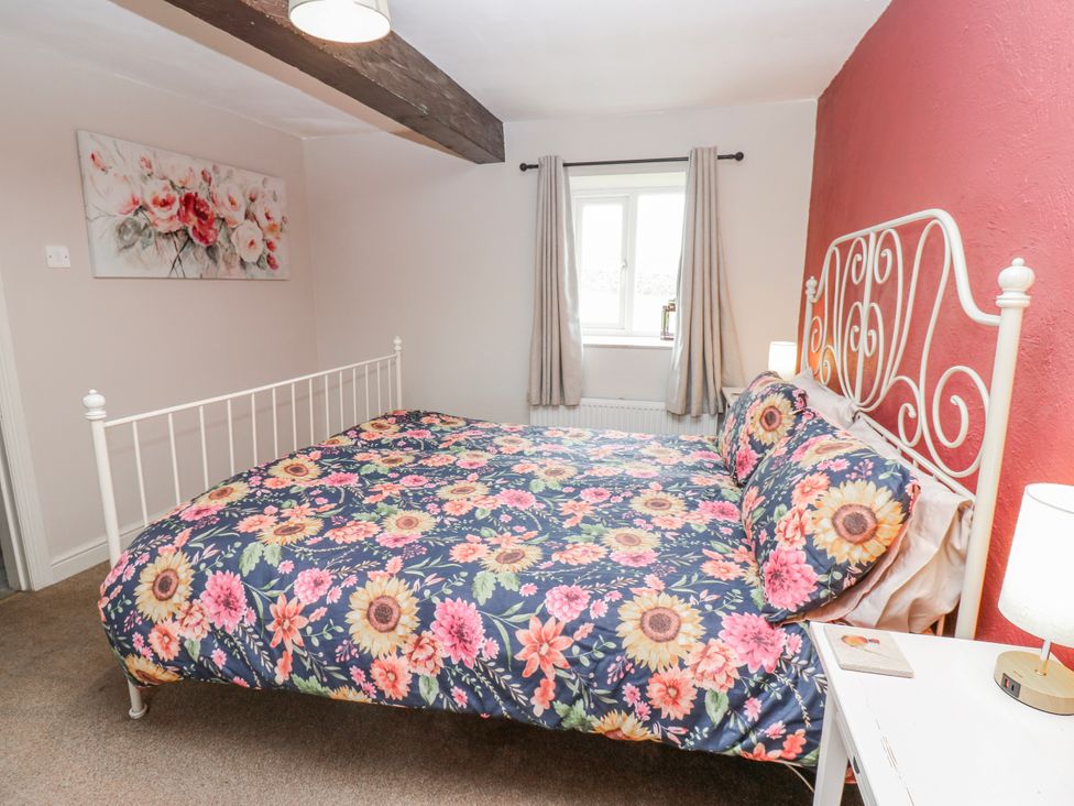 A bedroom with a floral bedspread and window at The Granary in Ellingstring near Masham