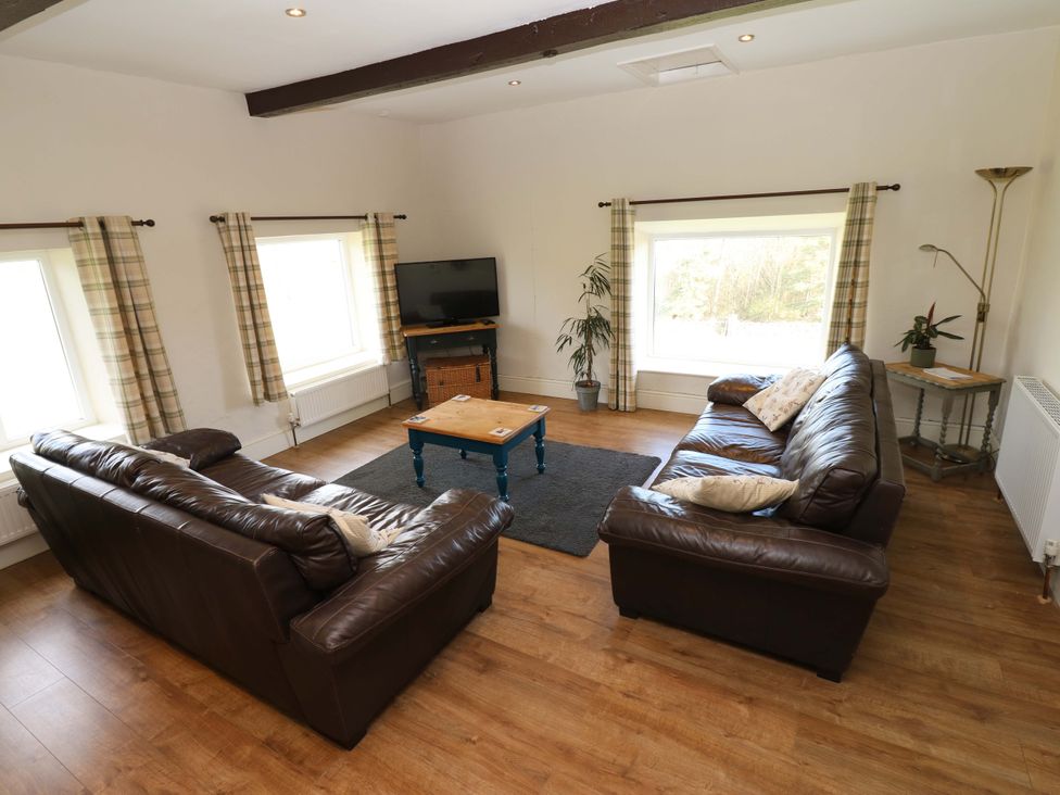 A living room with leather sofas and a coffee table at The Hayloft in Ellingstring near Masham