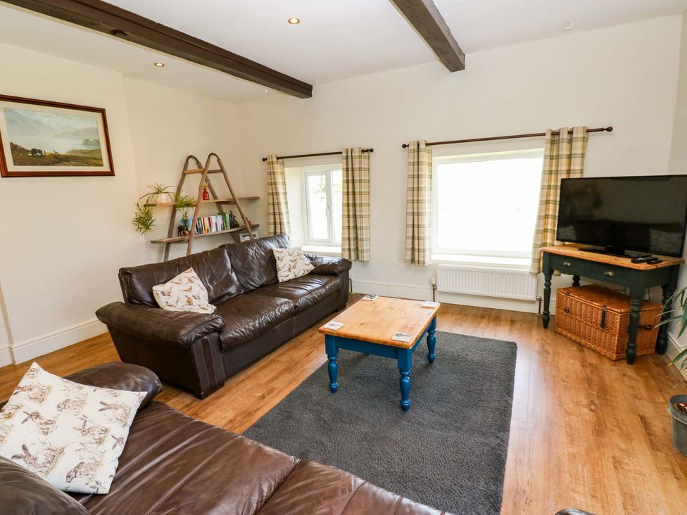 A living room with a sofa and a television at The Hayloft in Ellingstring near Masham