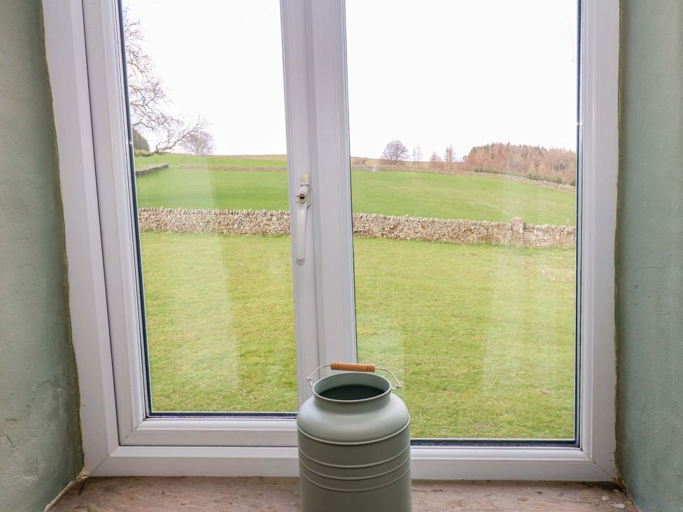 A window with a view of a green field and stone wall at The Hayloft in Ellingstring near Masham