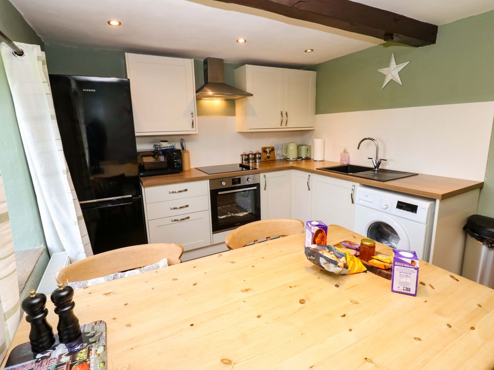 A kitchen with a table and various appliances at The Hayloft in Ellingstring near Masham