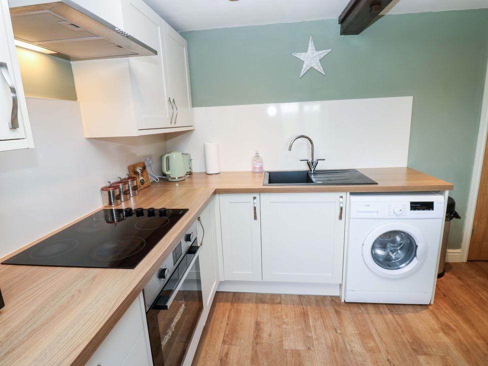A kitchen with sink, washing machine, kettle, and stove at The Hayloft in Ellingstring near Masham