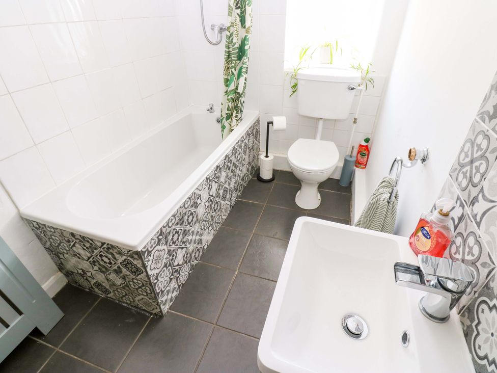 A bathroom with a bathtub, a toilet, and a sink at The Hayloft in Ellingstring near Masham