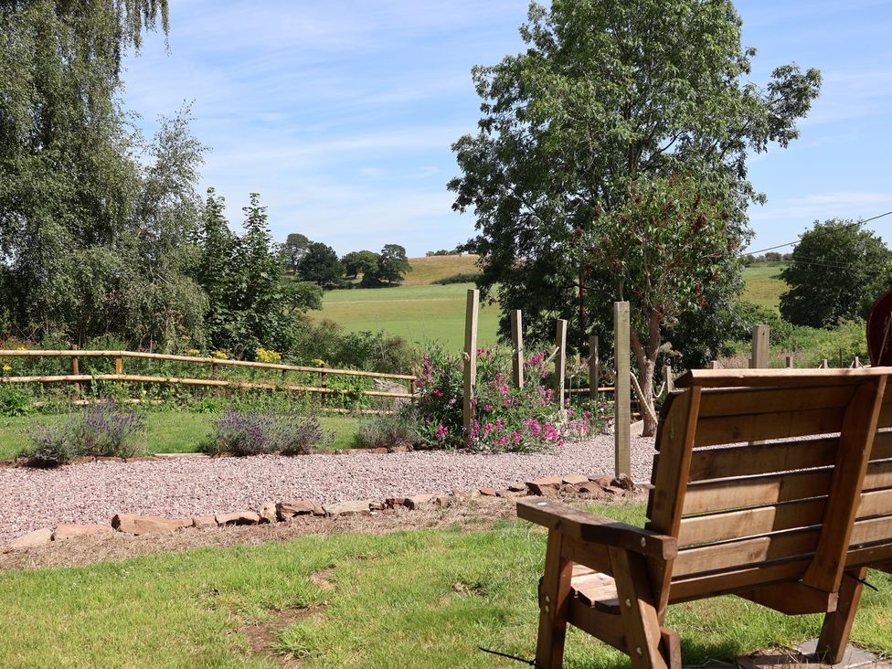 A garden with a bench and gravel path at 1 Fountain Cottages in Peckforton, Tarporley