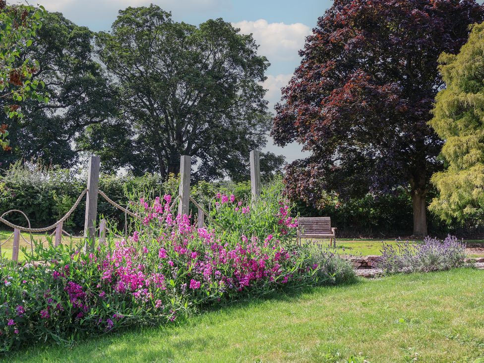A garden with flowers and trees at 1 Fountain Cottages in Peckforton, Tarporley