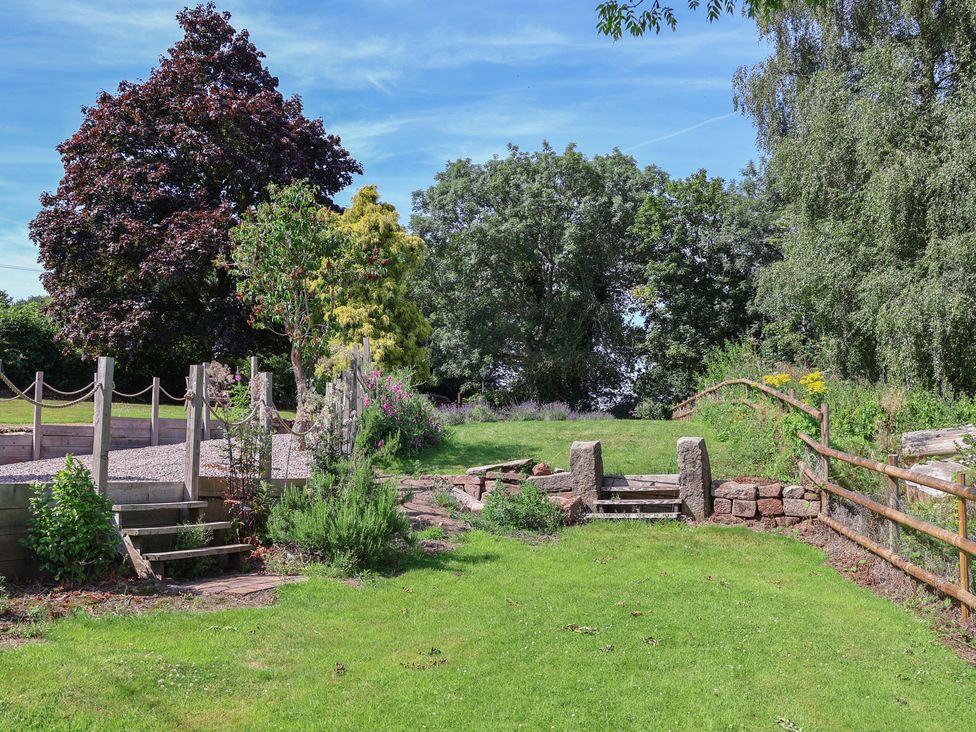 A garden with trees and a pathway at 1 Fountain Cottages in Peckforton, Tarporley