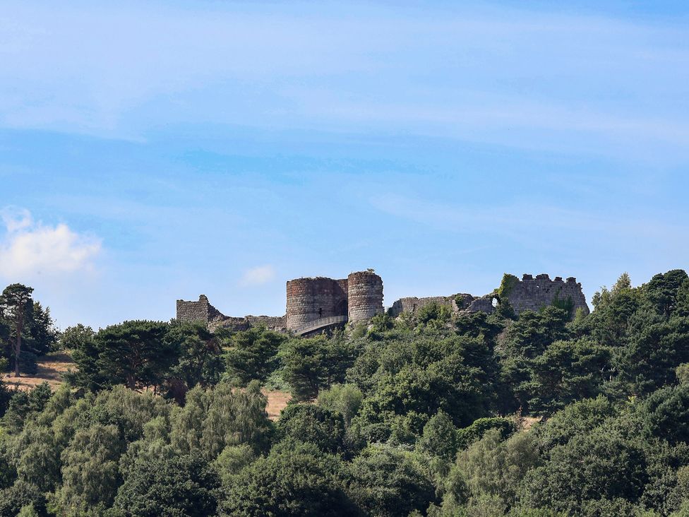 Castle ruins on a hill surrounded by trees at 1 Fountain Cottages, Peckforton, Tarporley