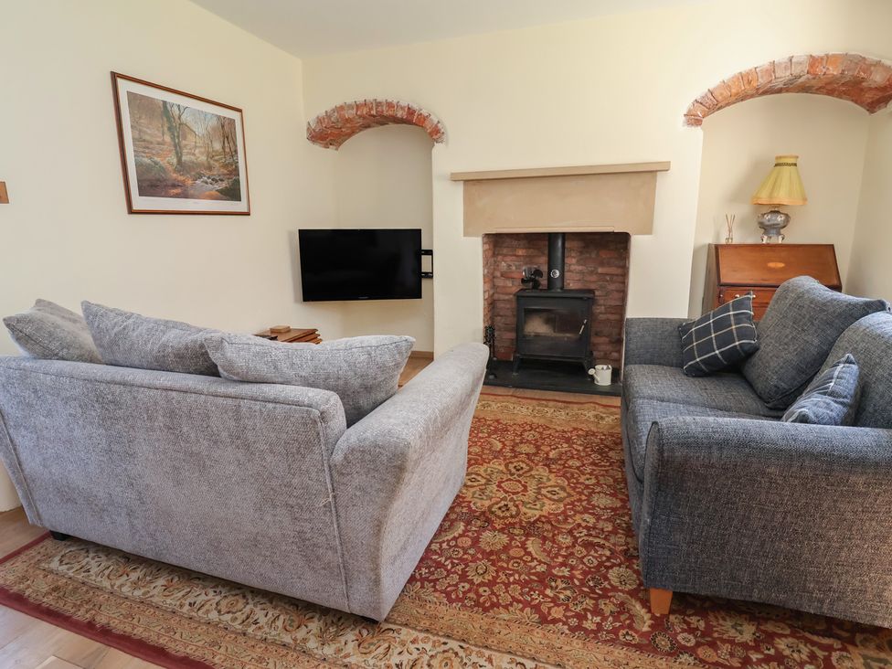 A living room with sofas and a fireplace at 1 Fountain Cottages in Peckforton, Tarporley