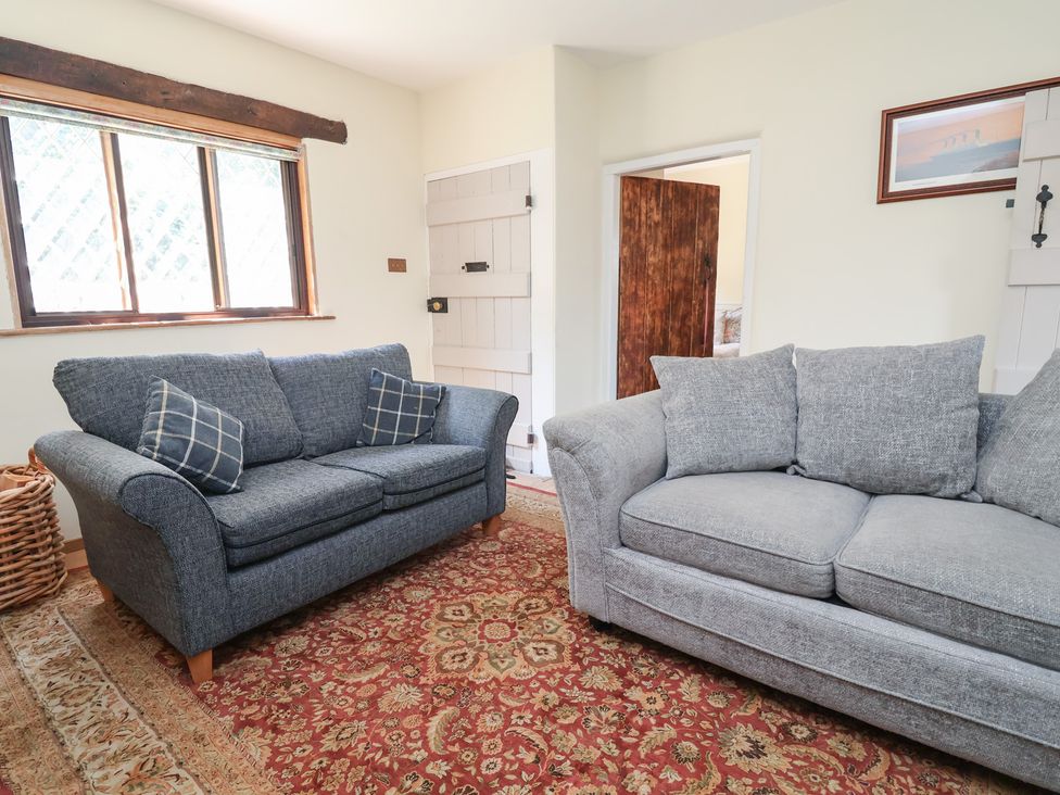 A living room with two sofas and a window at 1 Fountain Cottages in Peckforton, Tarporley