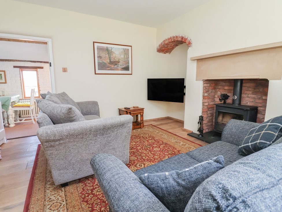 A living room with a fireplace and sofas at 1 Fountain Cottages in Peckforton, Tarporley