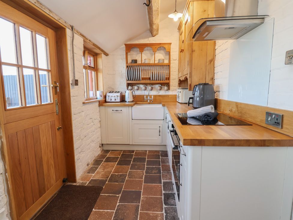 A kitchen with appliances and a door at 1 Fountain Cottages in Peckforton Tarporley