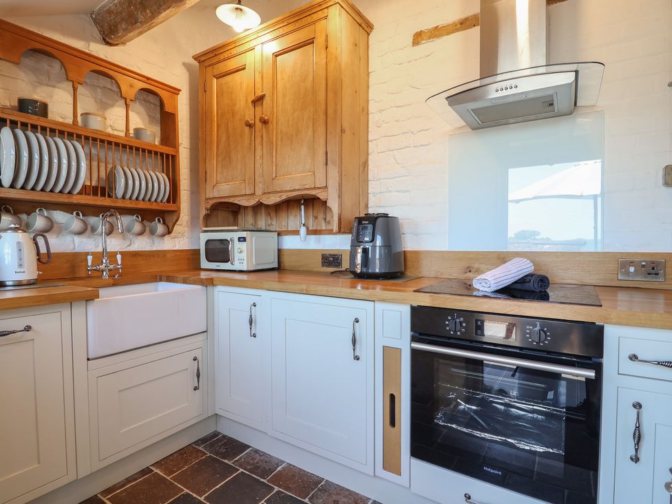 A kitchen with sink, microwave and oven at 1 Fountain Cottages in Peckforton, Tarporley