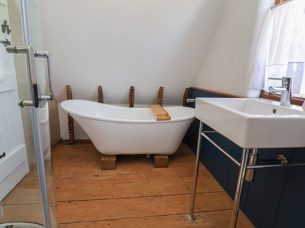A bathroom with a bathtub and wash basin at 1 Fountain Cottages, Peckforton, Tarporley