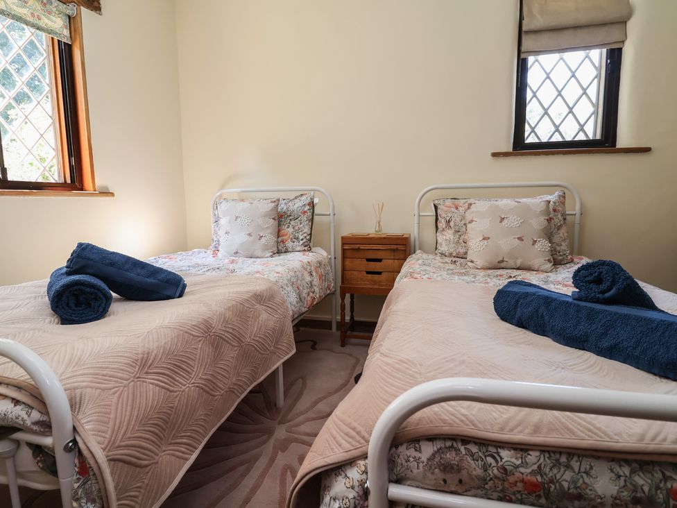 A bedroom with two single beds and a nightstand at 1 Fountain Cottages in Peckforton, Tarporley
