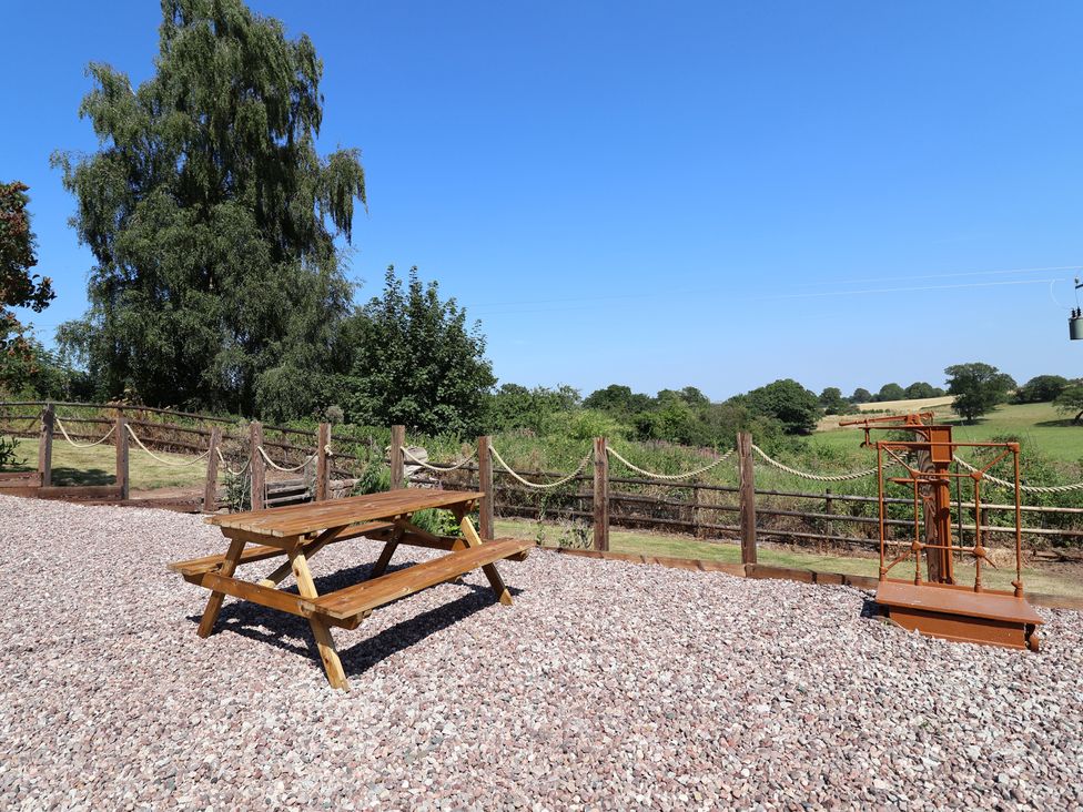 A picnic table and play equipment in a gravel area at 1 Fountain Cottages in Peckforton, Tarporley