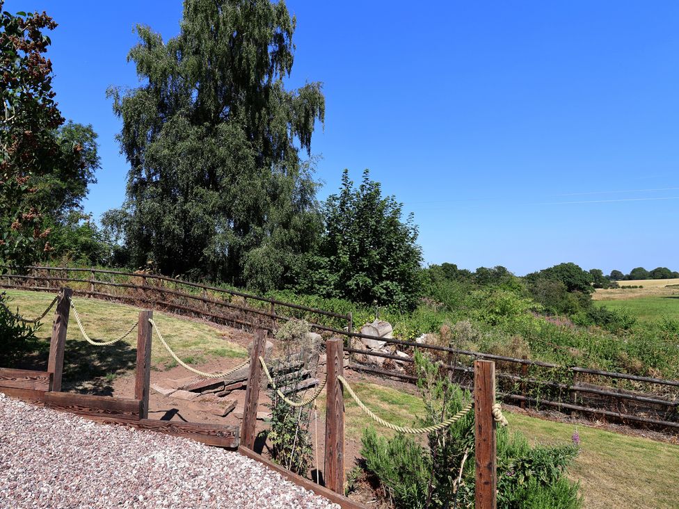 A garden with trees and a wooden fence at 1 Fountain Cottages in Peckforton, Tarporley