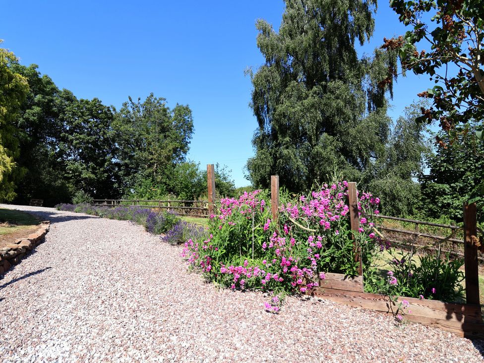 A gravel path with flowers and trees at 1 Fountain Cottages Peckforton, Tarporley